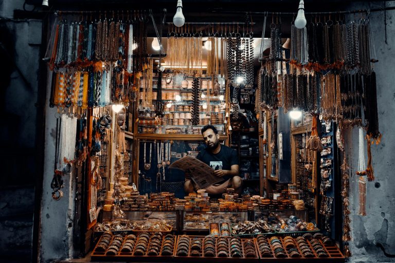 A man reads a newspaper in an intricately adorned jewelry shop in Pushkar, India at night.